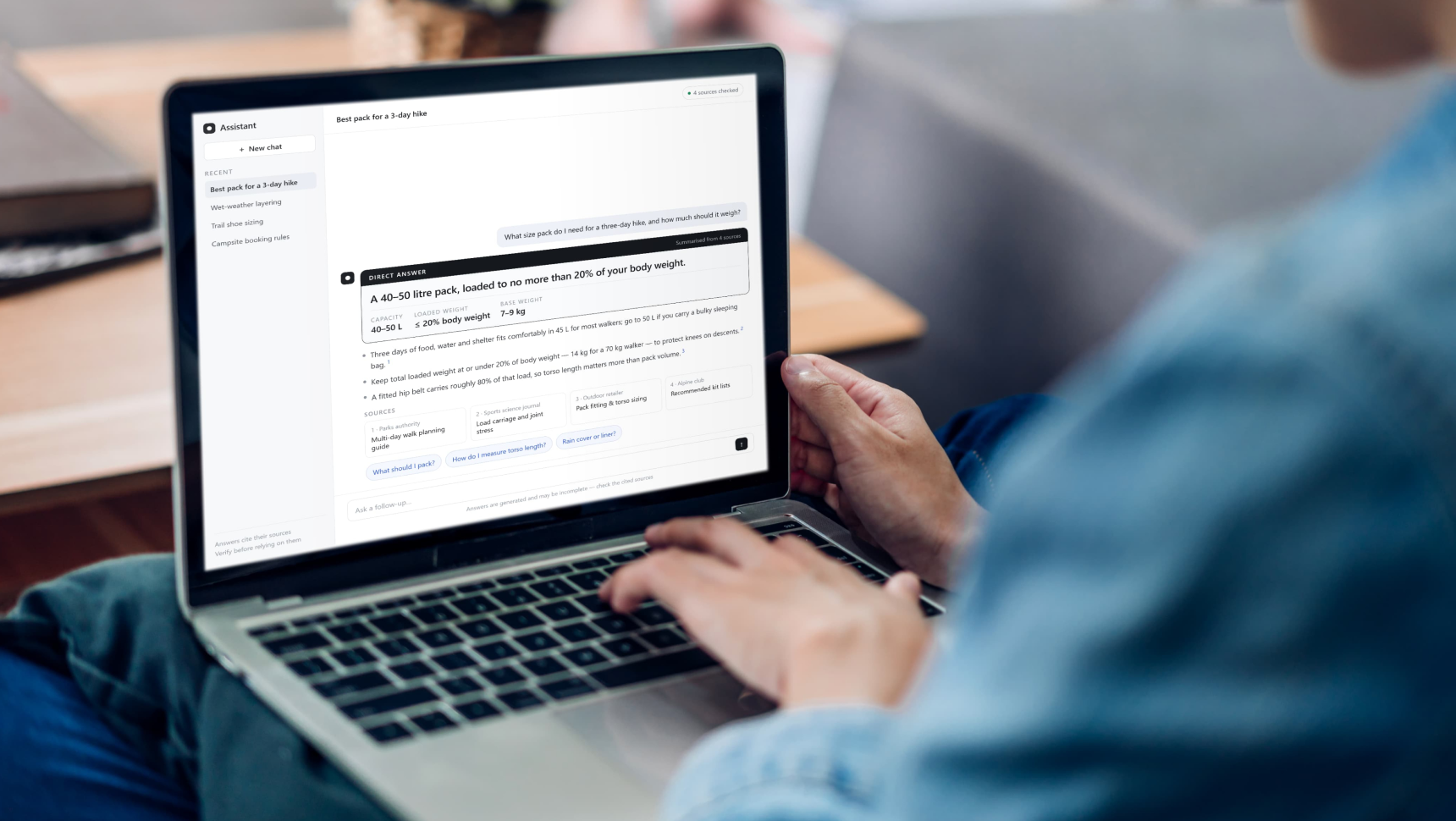 Laptop screen showing an AI assistant direct answer box with cited sources